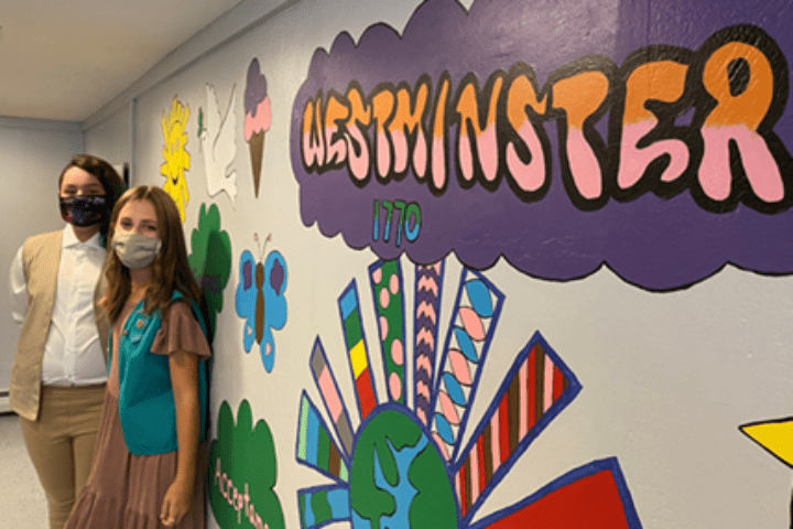 A girl standing in front of a wall with colorful designs on it.